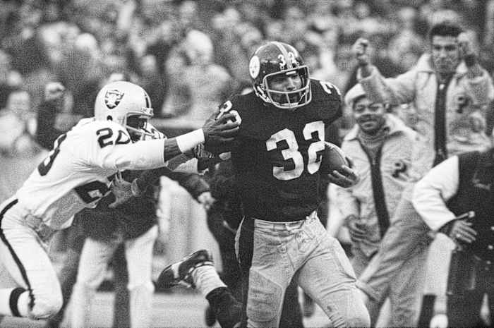 Franco Harris eludes a tackle by Oakland Raiders’ Jimmy Warren as he runs 42-yards for a touchdown after catching a deflected pass during an AFC Divisional NFL football playoff game in Pittsburgh on Dec. 23, 1972.